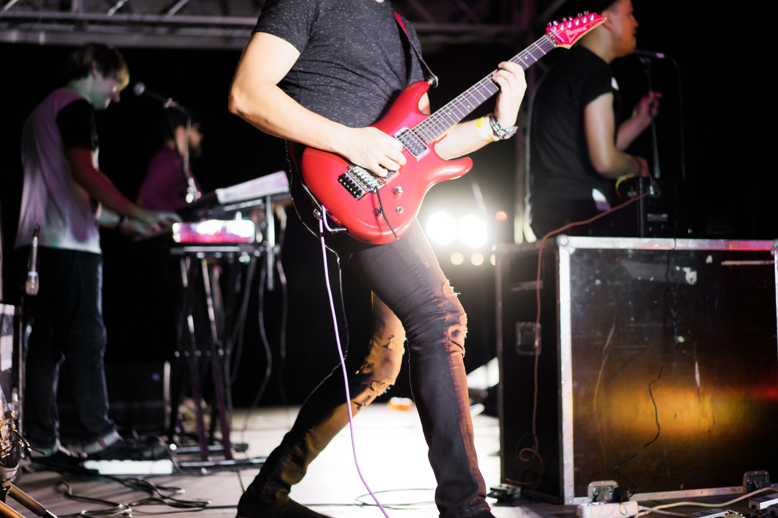 musicians on stage during a concert, guitarist with a red guitar, spotlights, feet of musicians of a wire of technics